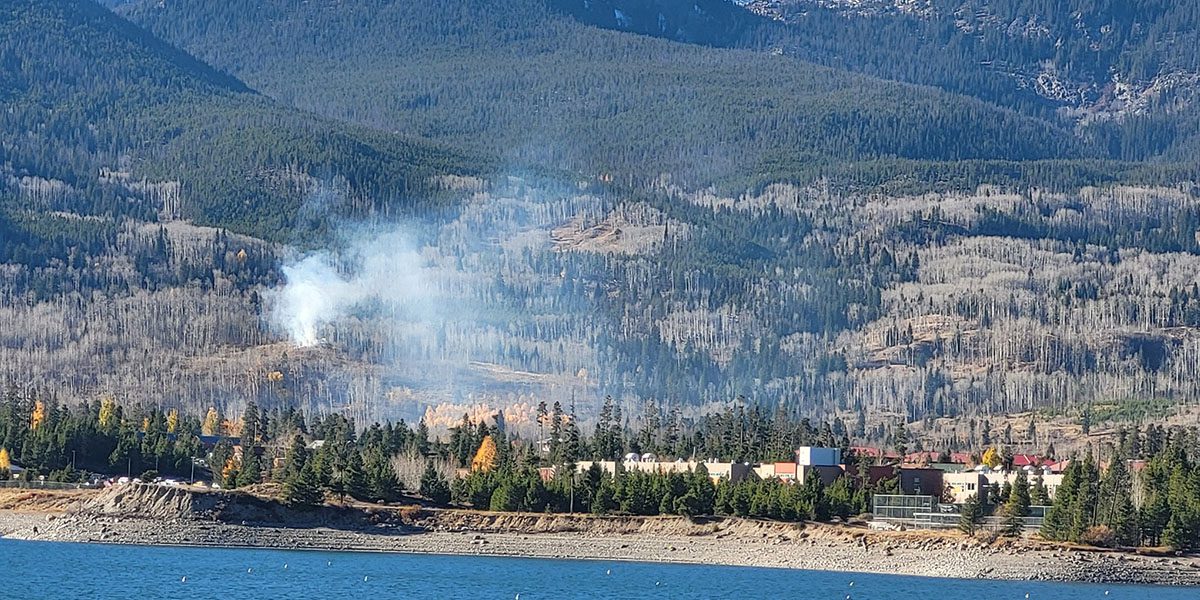 Wildfire with lake in the foreground and mountains in the background